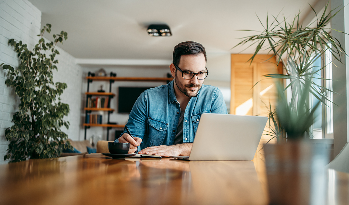 man taking notes looking at computer