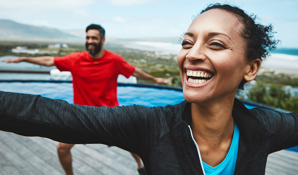 Couple doing yoga outside and smiling